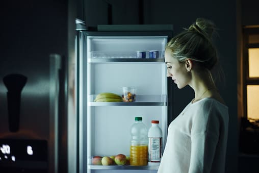 young woman looking for something healthy to eat in refrigerator